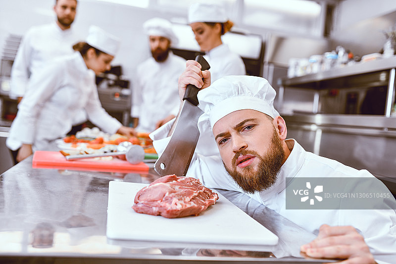 拿着牛排和切肉刀的英俊男厨师图片素材
