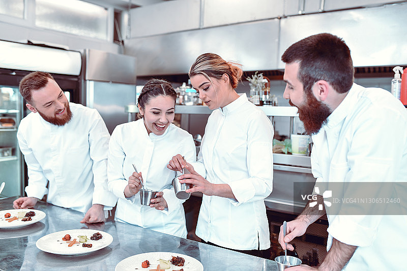 微笑女人观看年长的厨师在现代厨房里做甜点图片素材