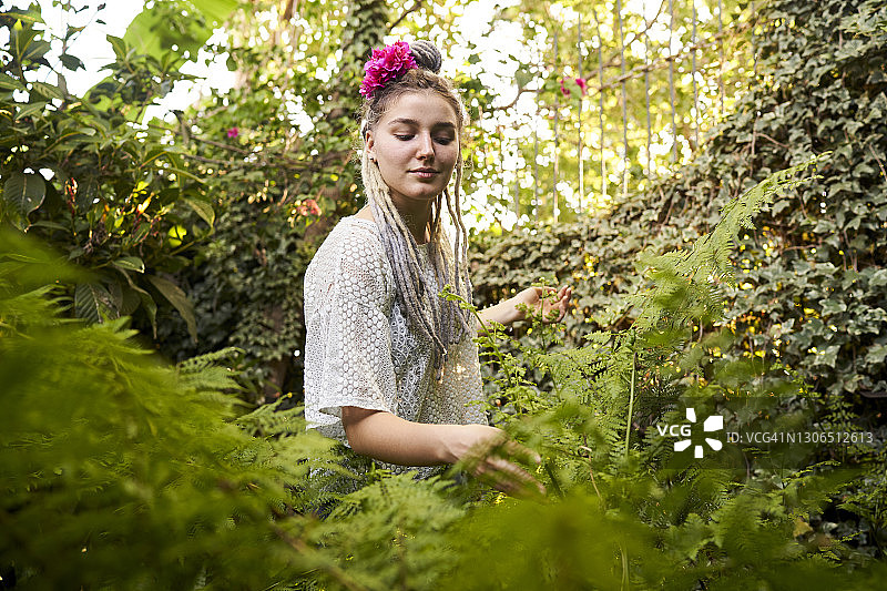 独自站在绿叶中的年轻女孩图片素材