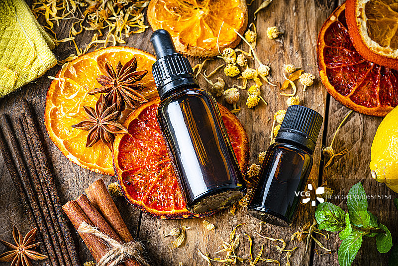 木桌上的芳香疗法：精油瓶、香薰、干橙和香料图片素材
