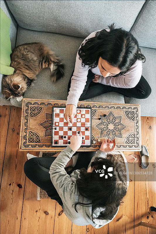 女孩在客厅和母亲下象棋图片素材