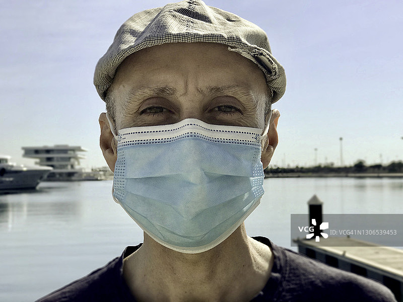 戴着防护口罩和鸭舌帽的户外男人图片素材