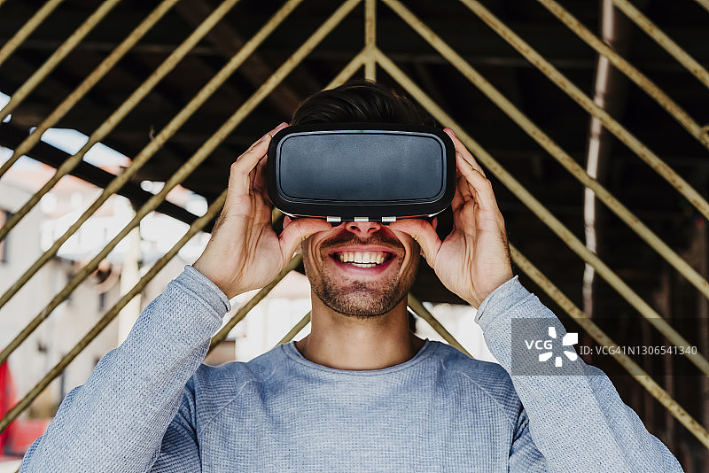 年轻男人使用VR眼镜，面露惊喜的笑容图片素材