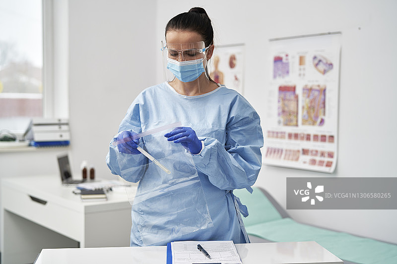 戴着面罩的中年女医生将医疗样本放入拉链袋中图片素材