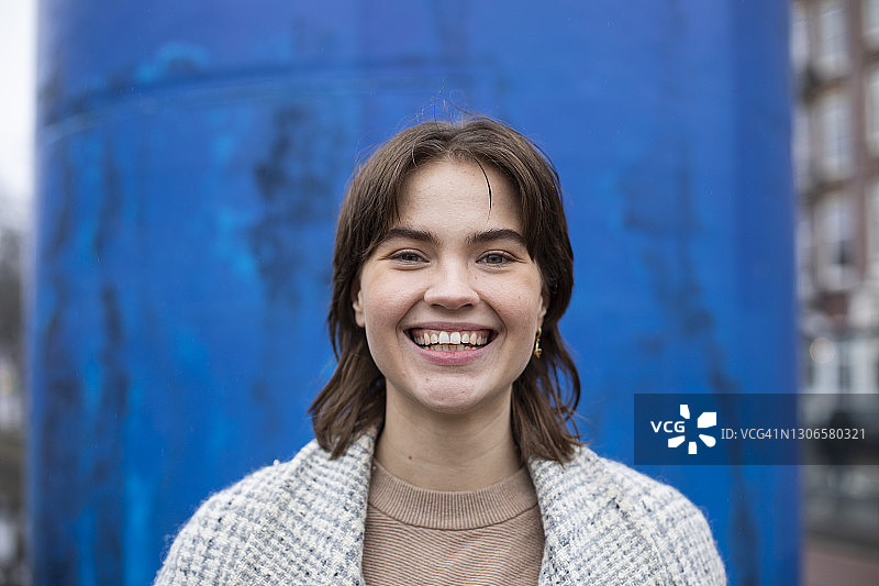对着蓝色建筑微笑的美丽女人图片素材