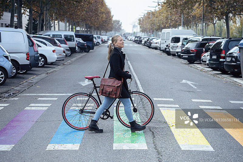 推着自行车走在斑马线上的女人，看向远方图片素材