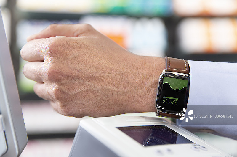 男人在药房使用智能手表进行非接触式支付图片素材