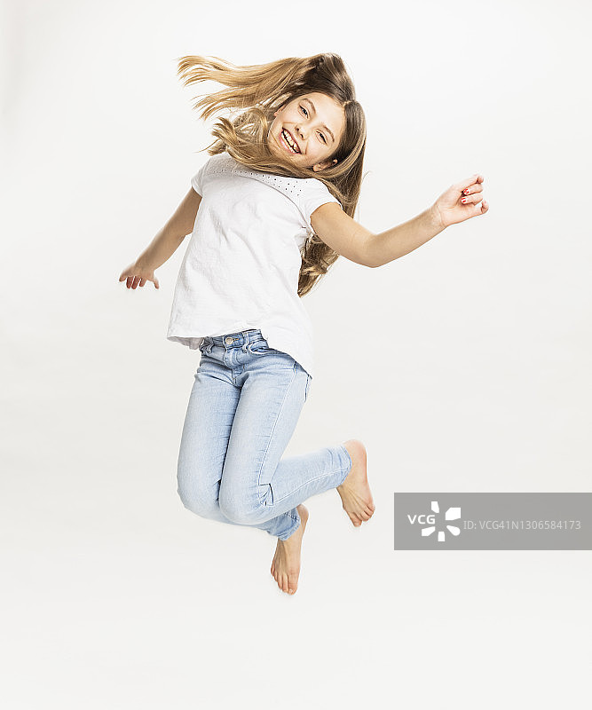 对着白色背景跳跃的微笑女孩图片素材
