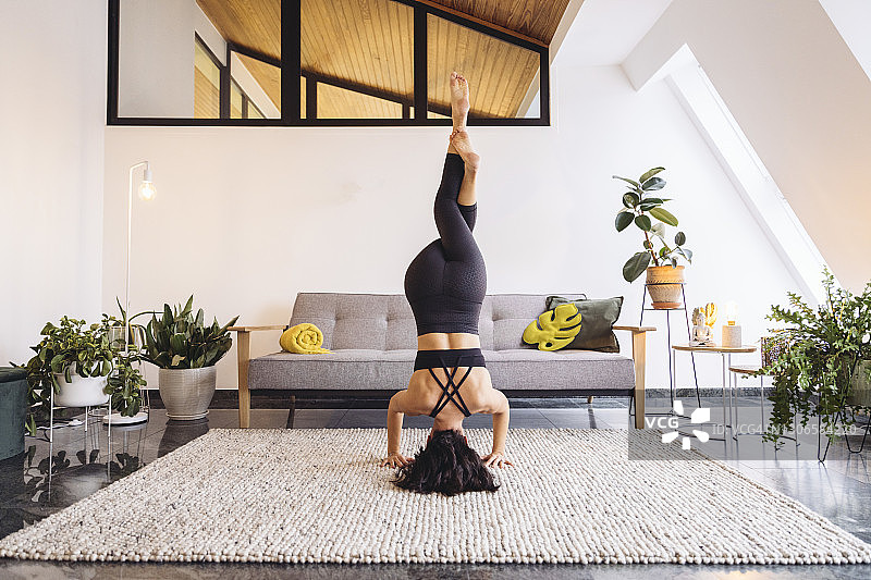 女人在家里的客厅练习头倒立图片素材