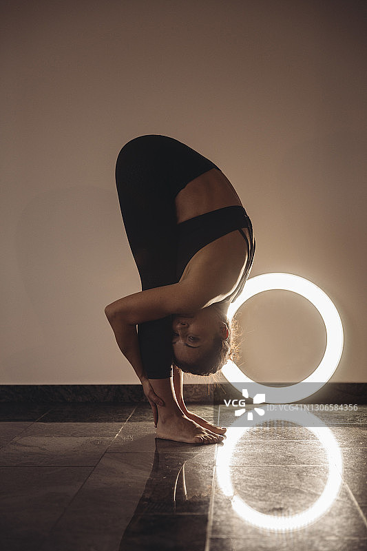 女人在家中环形灯前练习站立前屈图片素材