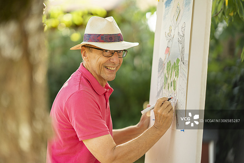 快乐的老年人戴着帽子在花园里绘画图片素材