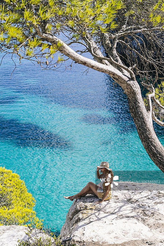 中年妇女坐在海边的岩石上休闲放松图片素材
