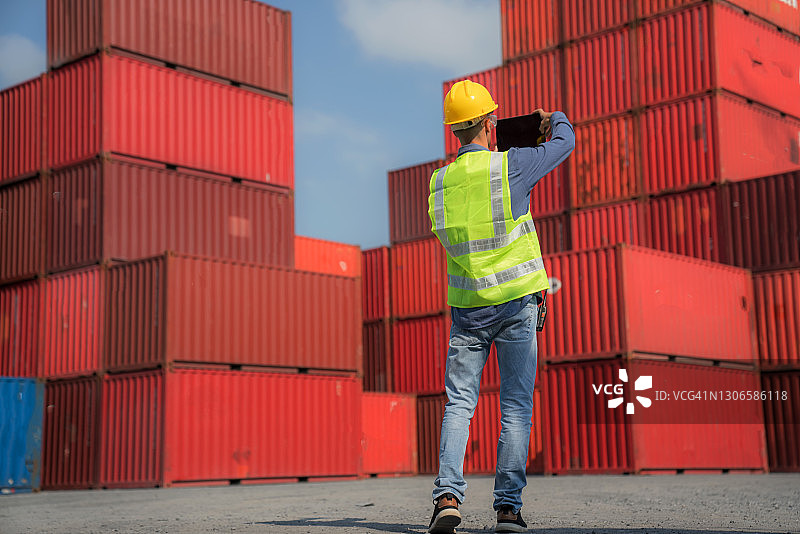戴着安全帽和安全背心的男工人在货船上控制装载集装箱图片素材