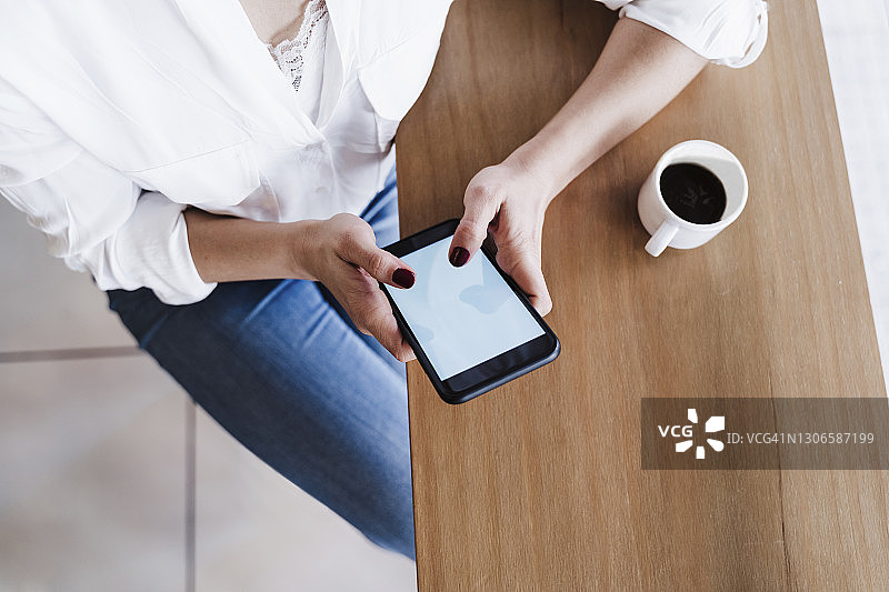 坐在办公室桌旁使用智能手机的女自由职业者图片素材