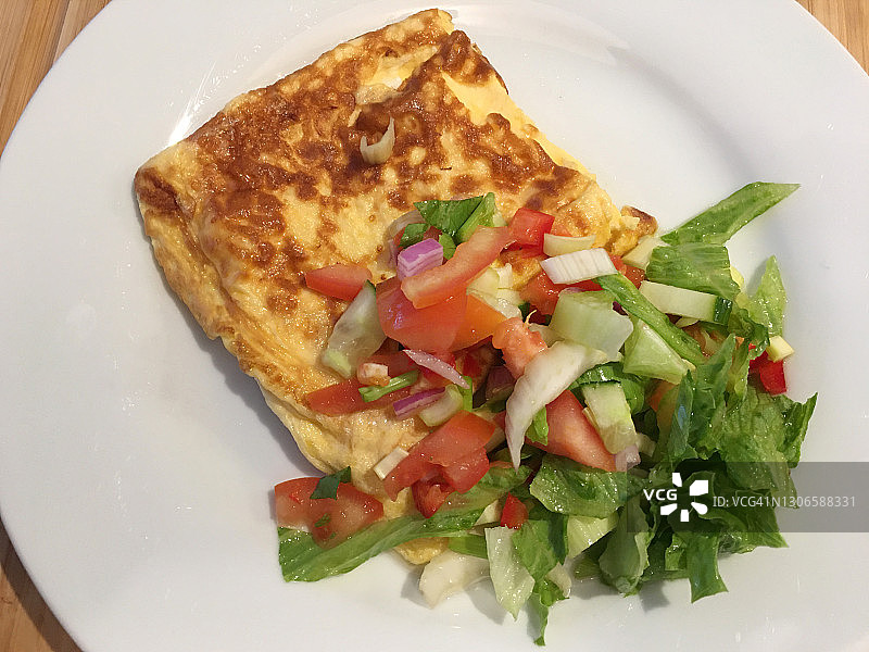 白色盘中搭配新鲜绿色沙拉的煎蛋卷图片素材