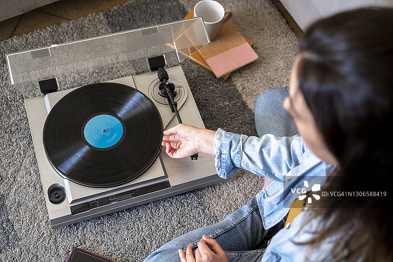 坐在家里地毯上播放唱片的女人图片素材