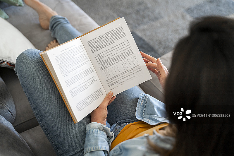 女人在家中沙发上放松地看书图片素材