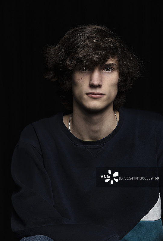黑色背景前的青少年男孩图片素材