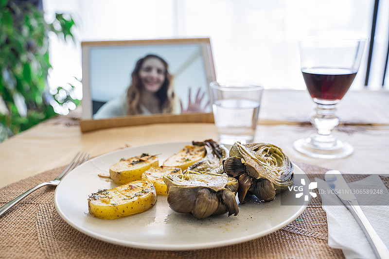 在餐桌旁享用午餐，同时观看平板电脑屏幕上的女性图片素材