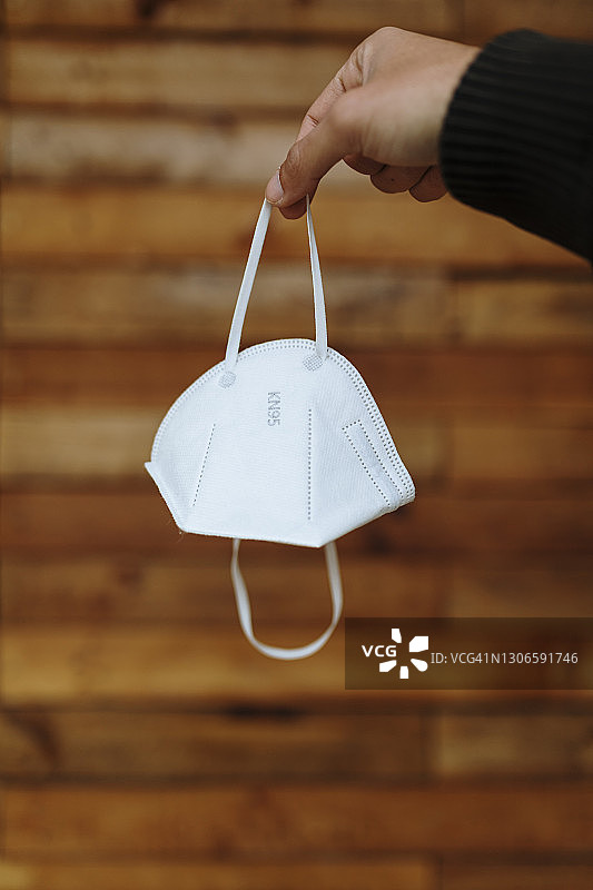 靠墙拿着防护口罩的男人图片素材