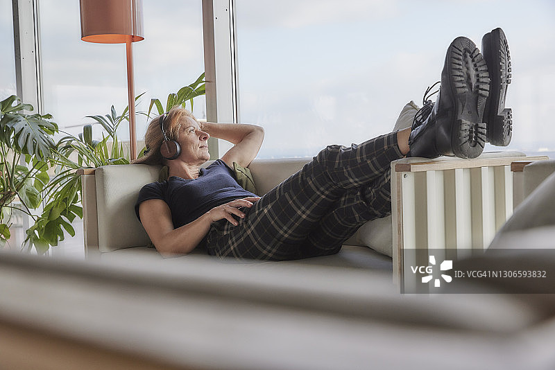 在家躺在沙发上听音乐，手放在头发里的女人图片素材