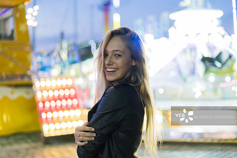 快乐的年轻女人在夜间的游乐场里图片素材