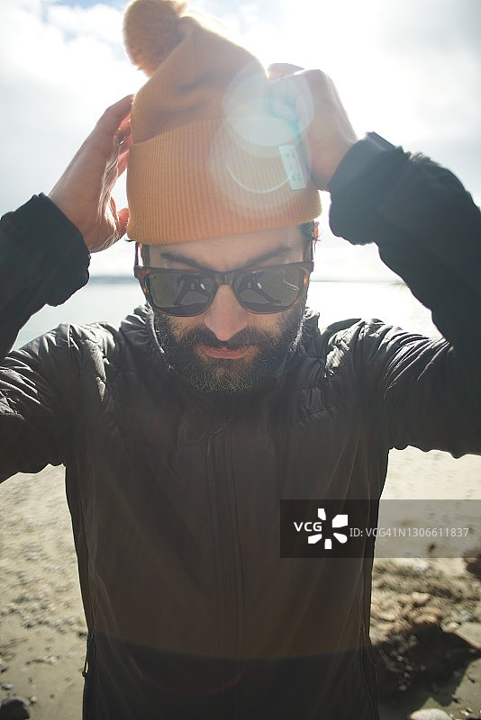 男人在沙滩上整理帽子图片素材