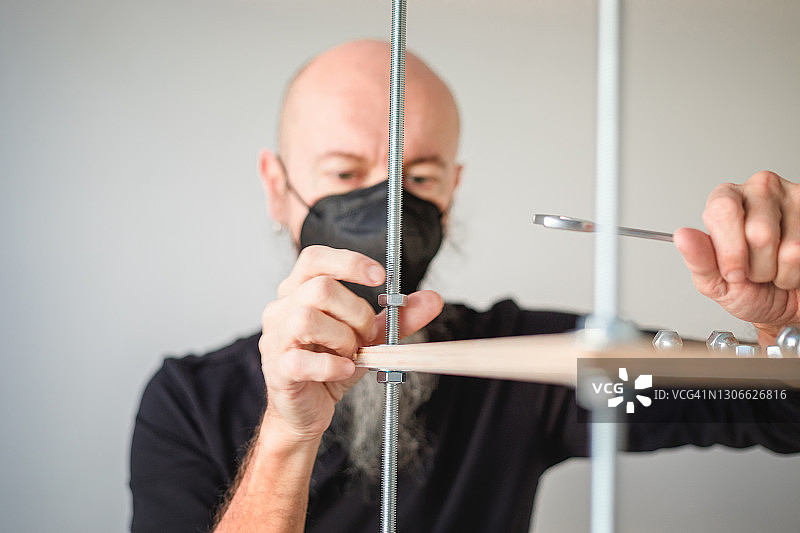 新冠肺炎隔离期间在家工作：男人组装胶合板工业风置物架图片素材