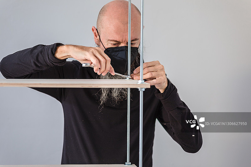 新冠肺炎隔离期间在家工作：男人组装胶合板工业风置物架图片素材