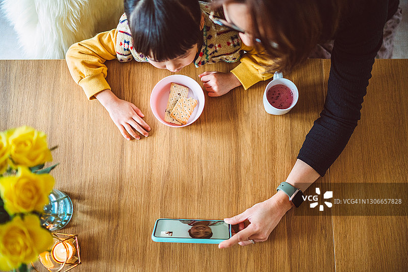 俯视：母亲和女儿在家用智能手机进行视频通话图片素材