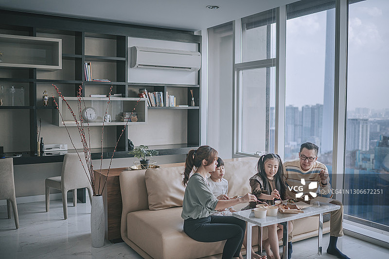 中国年轻家庭在周末于客厅电视前享用外卖图片素材