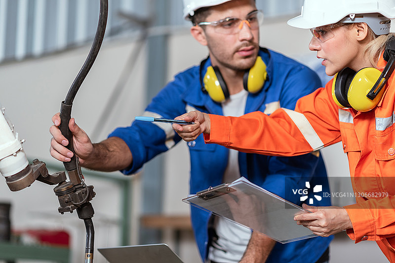 两位工程师在工厂检查自动化机械臂图片素材