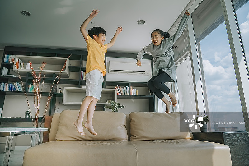 快乐的中国小男孩和小女孩在沙发上跳跃图片素材