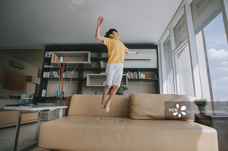 在沙发上快乐跳跃的亚洲男孩图片素材