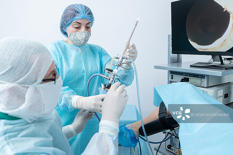 妇产科医生、妇科医生、生殖医学专家使用陀螺仪，护士协助医生进行宫腔镜手术图片素材