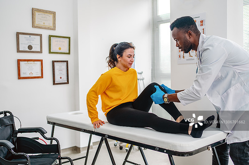 理疗师在诊所治疗受伤的女性运动员膝盖图片素材