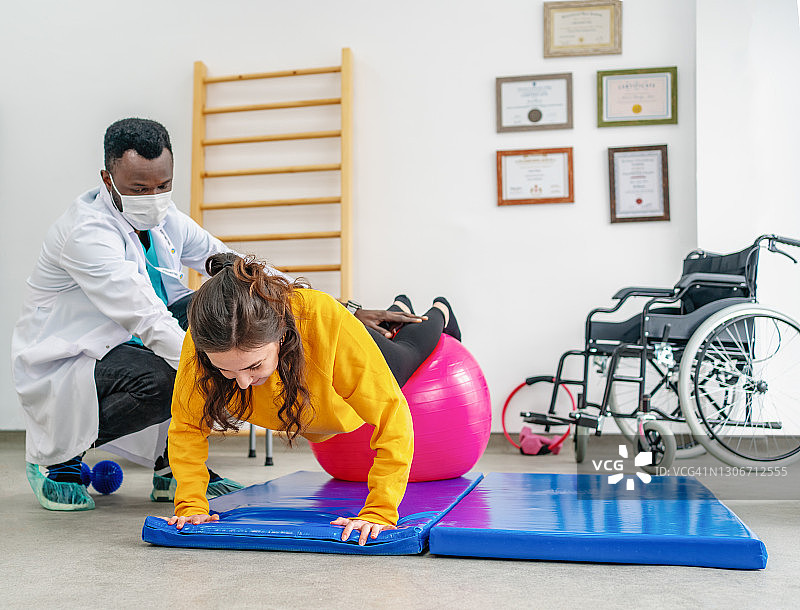 理疗诊所的专业理疗师为戴口罩的客户进行普拉提治疗图片素材