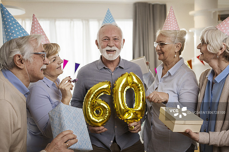拿着数字60，和最好的朋友一起庆祝生日，看着镜头的年长男人图片素材