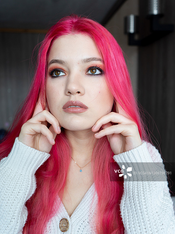 棕色眼睛的女孩，手摸着被粉色头发遮住的耳朵图片素材