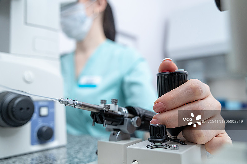在试管婴儿诊所的实验室中，胚胎学家的手在倒置显微镜下操作图片素材