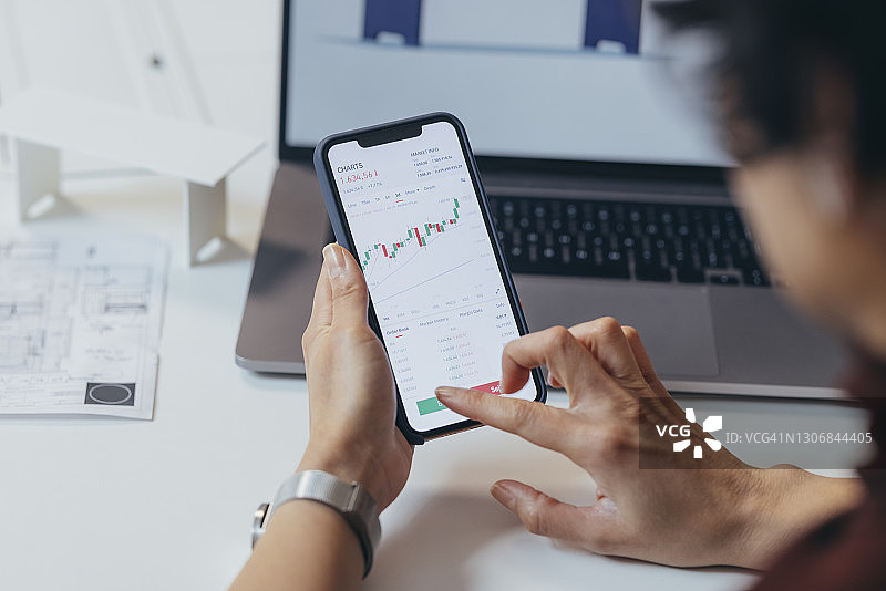 匿名金融专家用智能手机分析财务图表图片素材