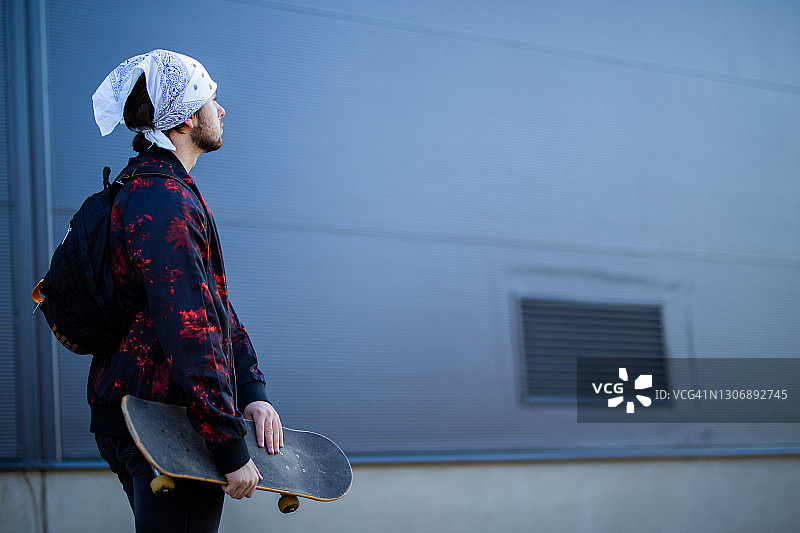 拿着滑板仰望天空的年轻人图片素材