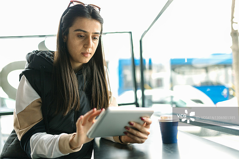 在咖啡馆使用平板电脑的年轻女人图片素材