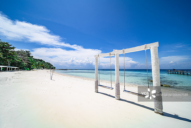 白色沙滩和水晶般蓝色海水中的白色秋千图片素材