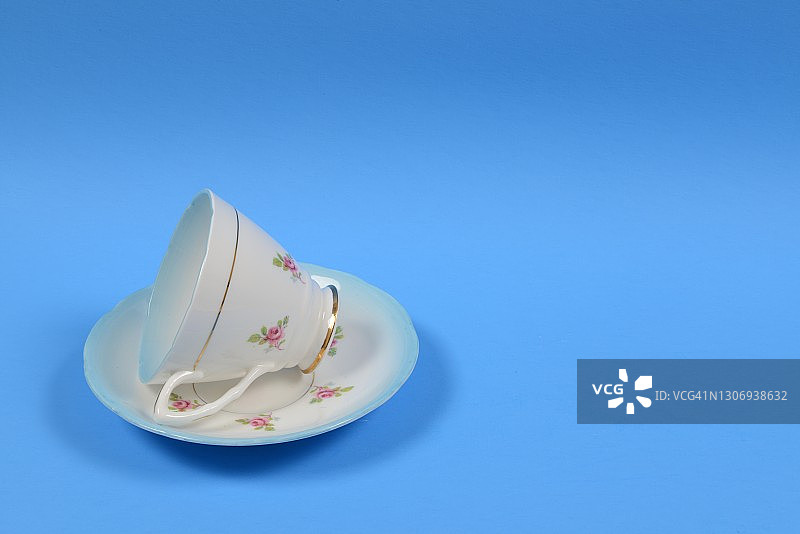 复古茶杯茶碟，粉色花朵蓝色背景图片素材