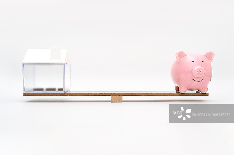 木质天平上的储蓄罐和房屋模型图片素材