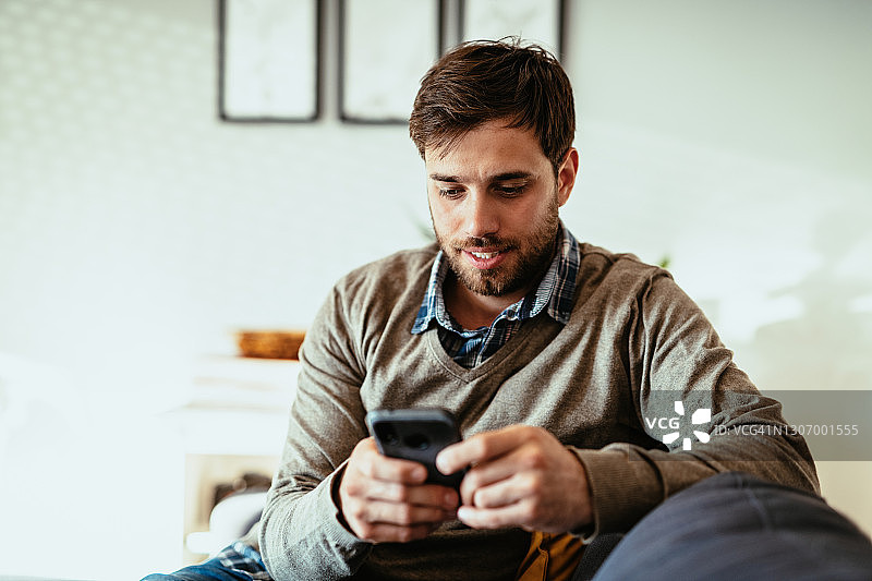 千禧一代男子在家工作使用智能手机图片素材