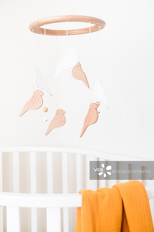 婴儿房特写：白色婴儿床和悬挂的摇铃图片素材