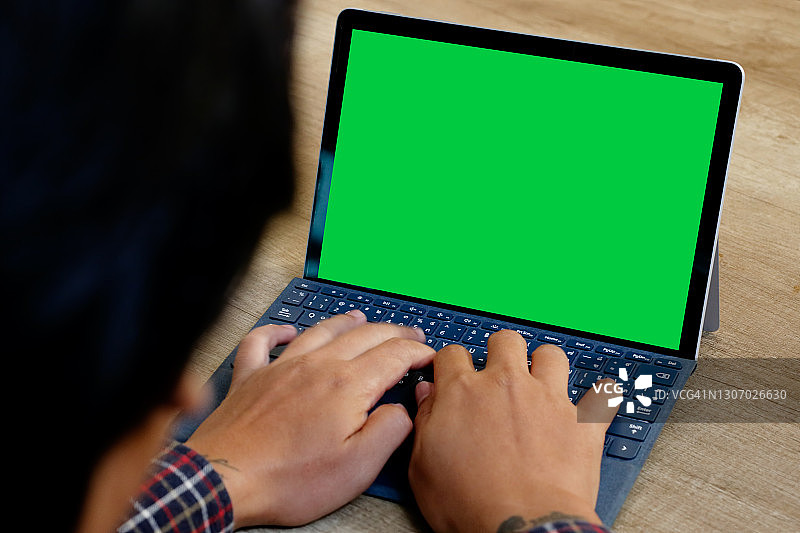 在绿屏笔记本电脑上工作的男人图片素材