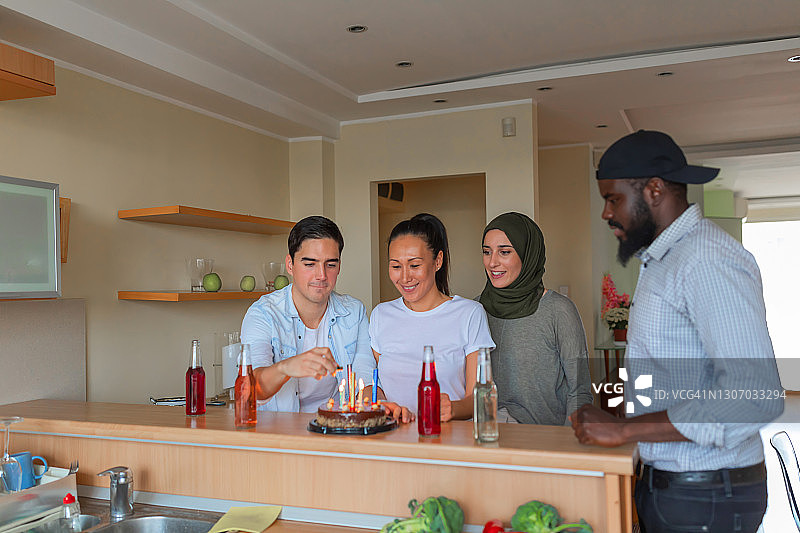 一群快乐的年轻多元文化朋友正在用生日蛋糕和饮料庆祝年轻男子的生日图片素材